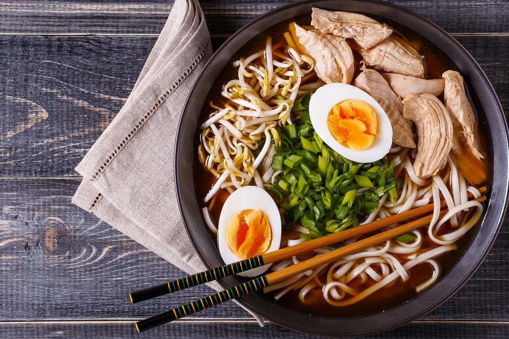 Japanese ramen soup with chicken, egg, chives and sprout on dark wooden background