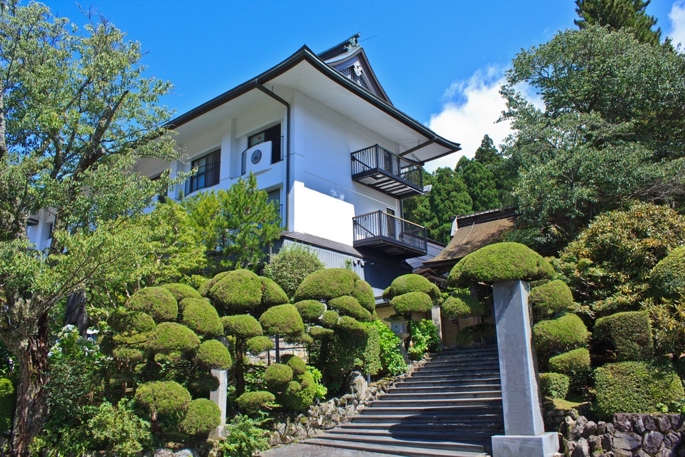 A lush Japanese garden of topiary trees and shrubs lines the entrance to a Buddhist temple in Koyasan