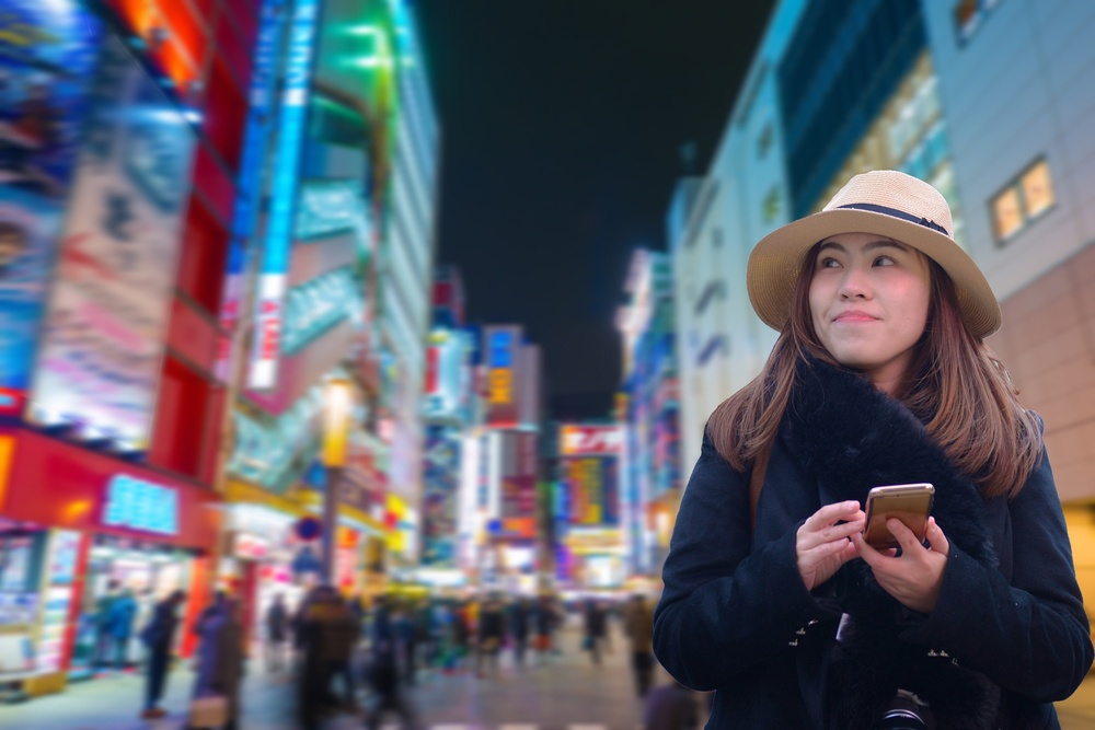 Asian woman tourist is using smart phone connecting at Akihabara back ground in Tokyo, Japan
